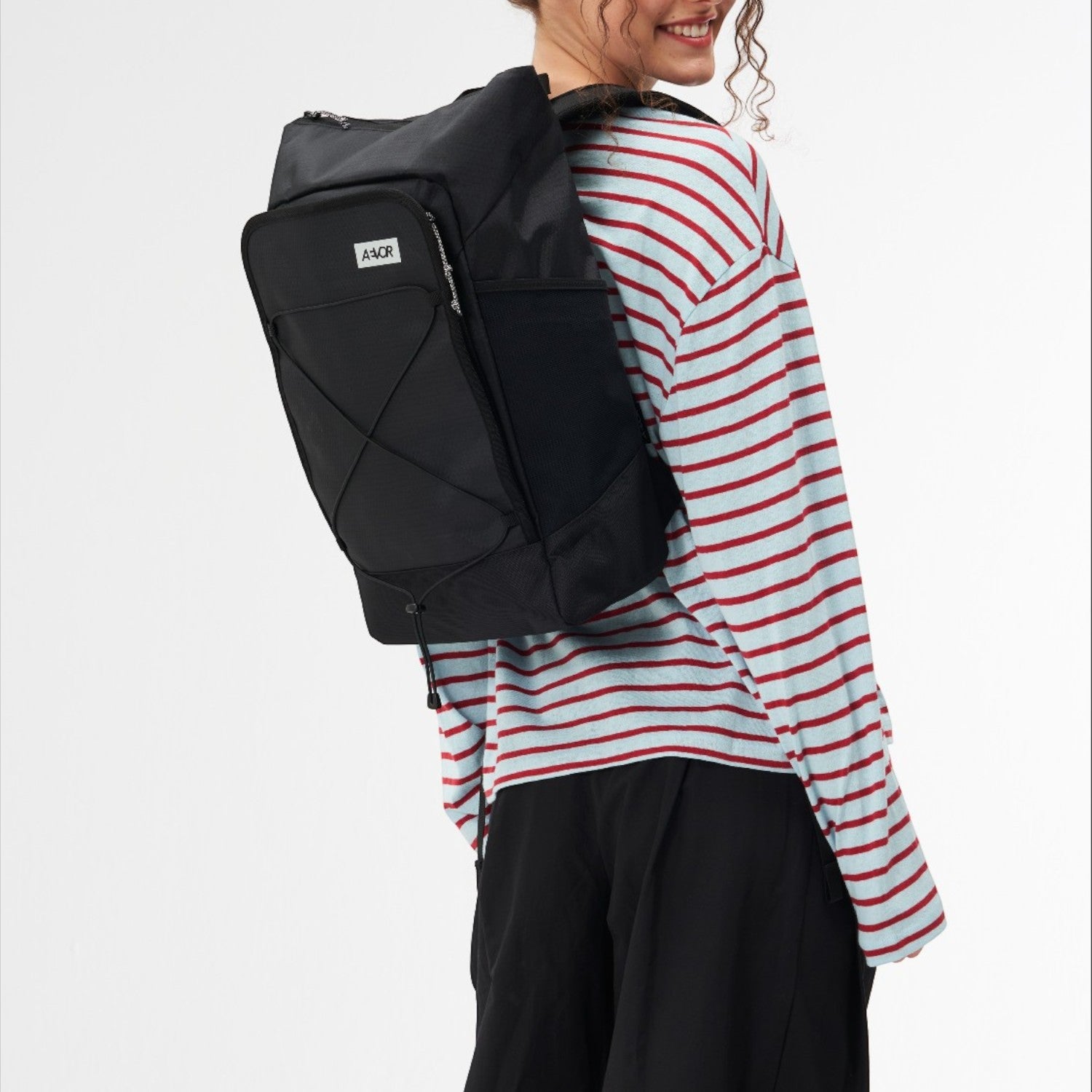 Lieblingstasche Day Pack FLX in black worn by a smiling woman in a striped long-sleeve shirt