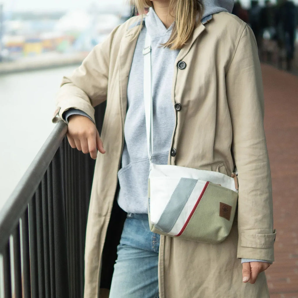 Lieblingstasche Deern Lütt crossbody bag in white, grey, and olive green with a striped accent worn by a woman