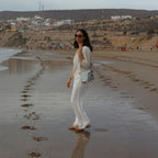 Woman wearing a Lieblingstasche Deern Lütt crossbody bag on a sandy beach at sunset