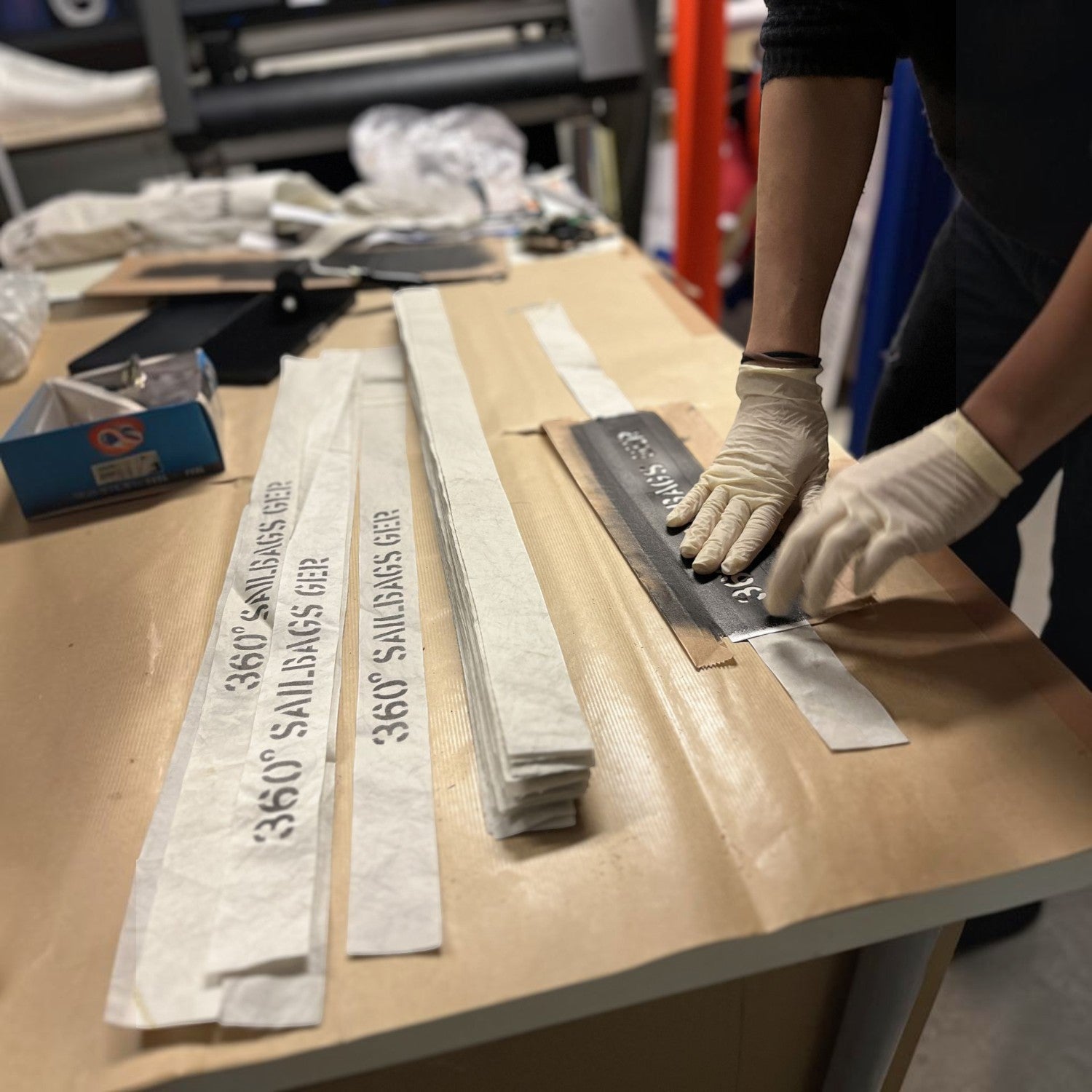 Lieblingstasche Deern Lütt bag production process showing hands applying branded sailcloth strips to a template