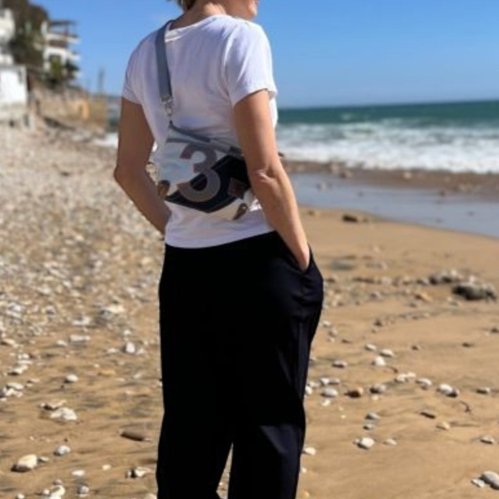 Lieblingstasche Deern Lütt crossbody bag made from recycled sailcloth with number print, worn by woman on the beach