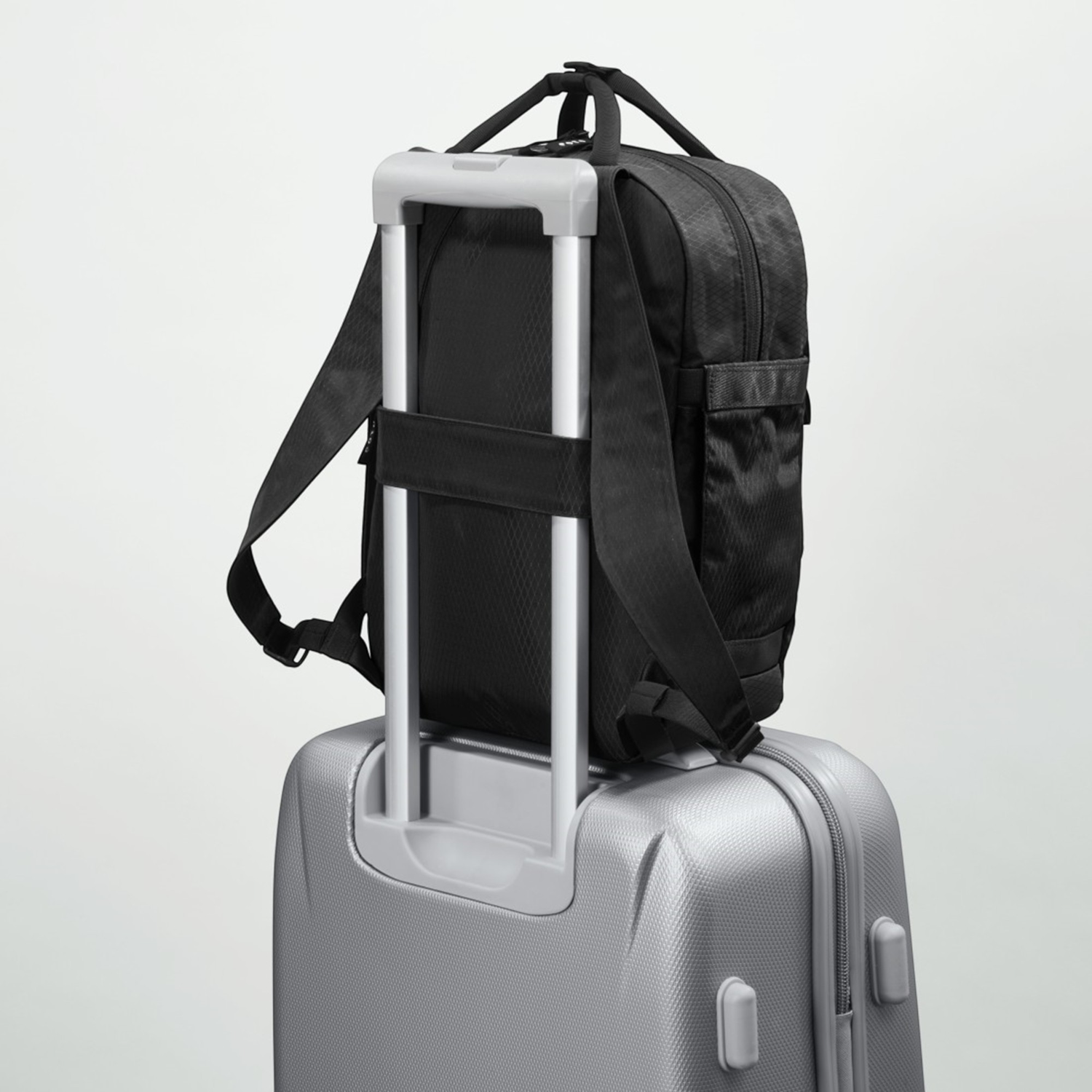 Lieblingstasche eoto Small16 black daypack attached to a silver suitcase handle for travel