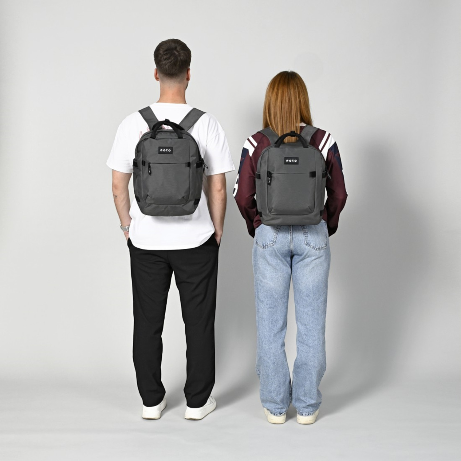 Lieblingstasche eoto Small16 grey compact daypack worn by a man and a woman in a studio setting