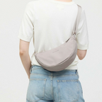 Lieblingstasche Essential Moon Bag in light grey worn as a crossbody bag by a woman in a white top and jeans