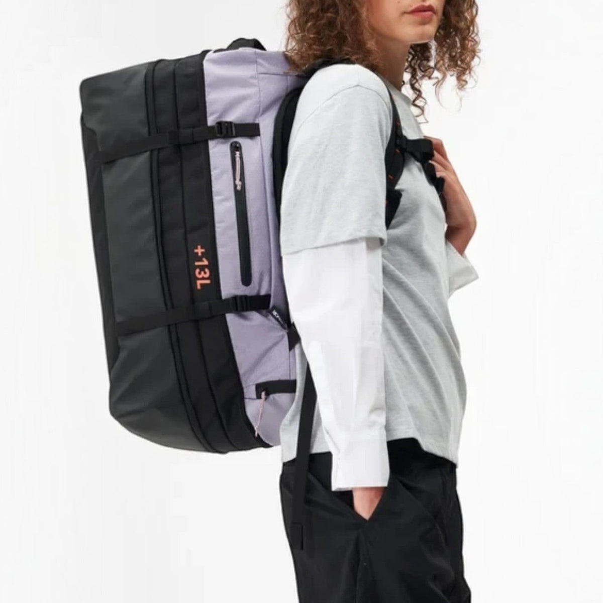 Model wearing a Lieblingstasche black and grey expandable duffel backpack with 47-60L capacity for travel and sports.