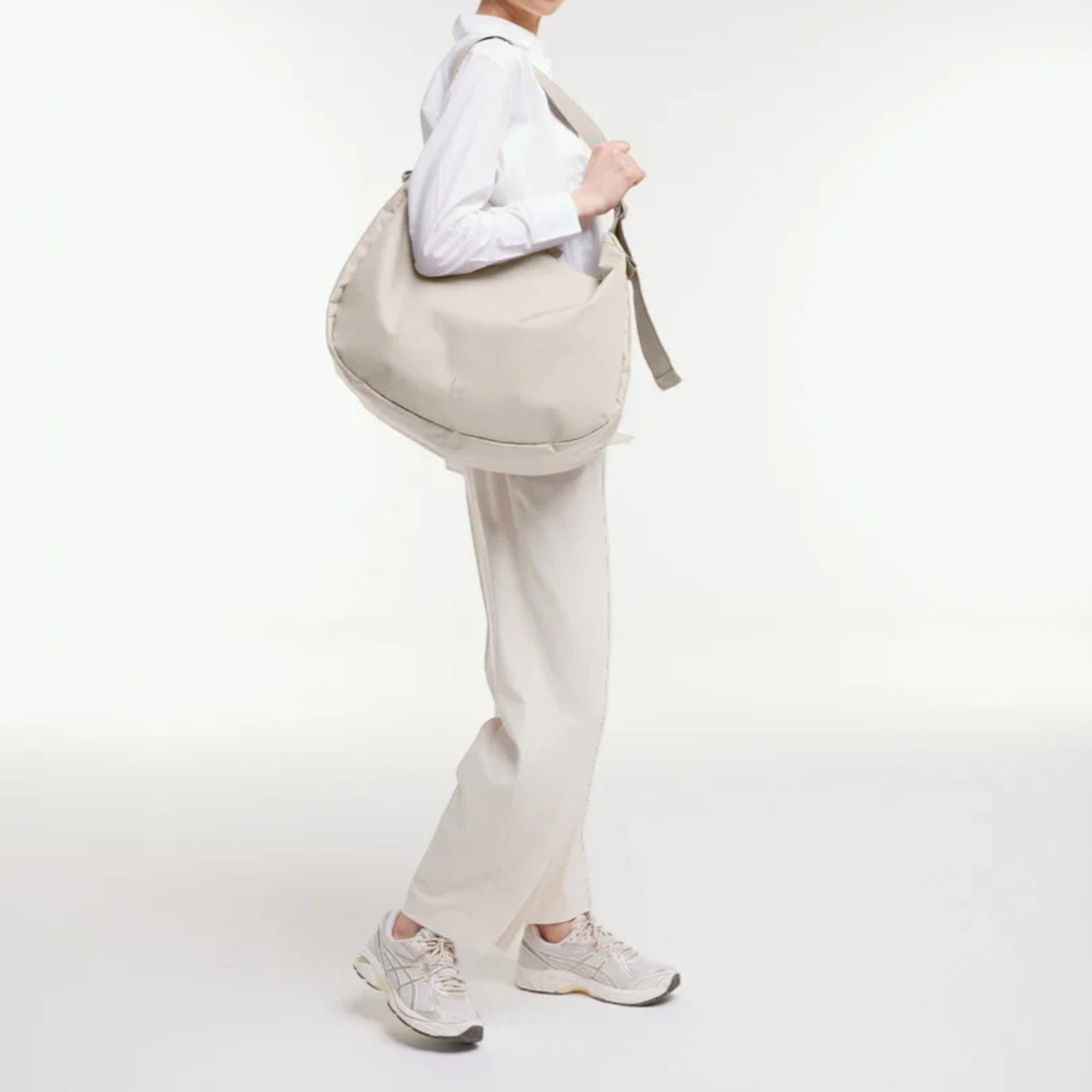 Lieblingstasche GOT BAG curved shoulder bag in beige worn by a model in a white outfit against a studio background