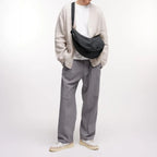 Lieblingstasche GOT BAG Moon Bag Large in black worn crossbody by a man in a beige cardigan and grey trousers