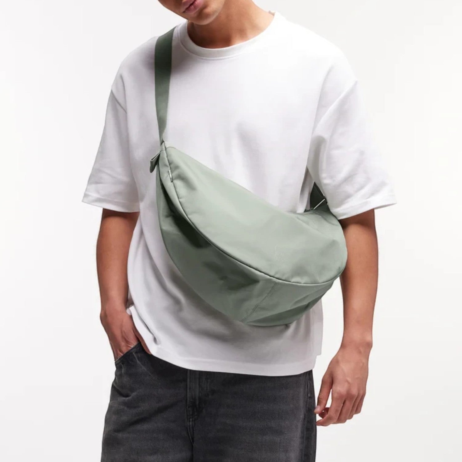 Man wearing a sage green GOT BAG Moon Bag Large crossbody, styled with a white t-shirt from Lieblingstasche