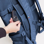 Lieblingstasche GOT BAG Rolltop 2.0 backpack in blue with a hand placing a smartphone into the back security pocket