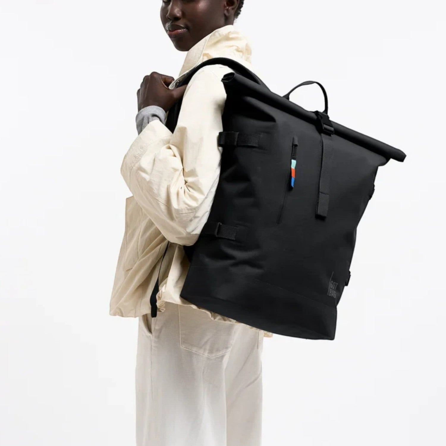 Model wearing a black GOT BAG Rolltop 2.0 backpack from Lieblingstasche, featuring a flexible magnetic closure.