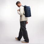 Lieblingstasche GOT BAG Rolltop Lite 2.0 backpack in navy blue worn by a man in a white sweater and grey jeans
