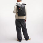 Lieblingstasche GOT BAG Rolltop Lite 2.0 black backpack worn by a man in a white sweater and dark jeans