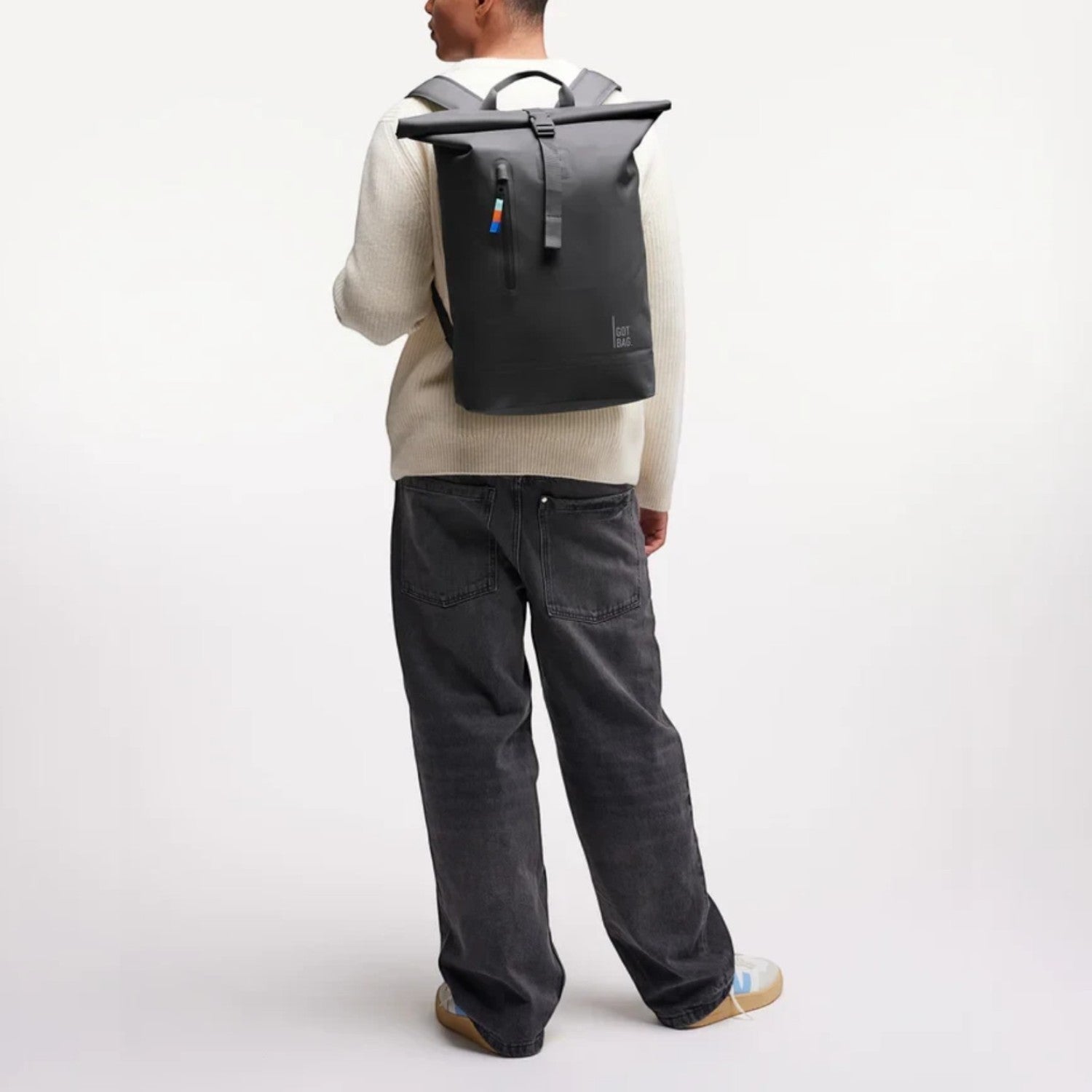 Lieblingstasche GOT BAG Rolltop Lite 2.0 black backpack worn by a man in a white sweater and dark jeans