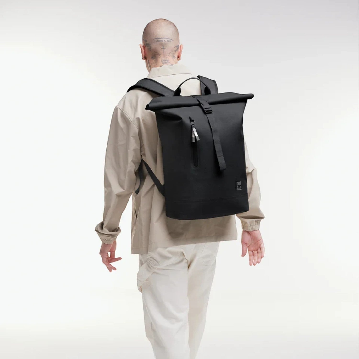 Lieblingstasche GOT BAG Rolltop Lite 2.0 black backpack worn by a man in a beige jacket against a white background
