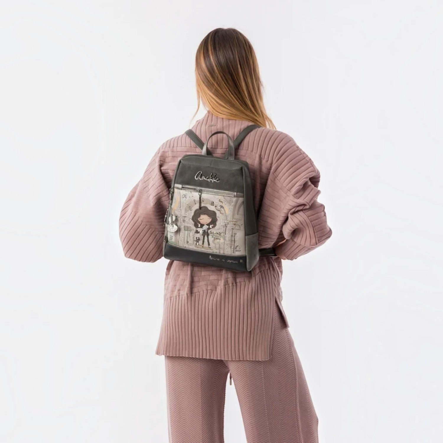 Lieblingstasche grey backpack with Anekke illustration, front zip pocket, and metallic charm on a woman's back
