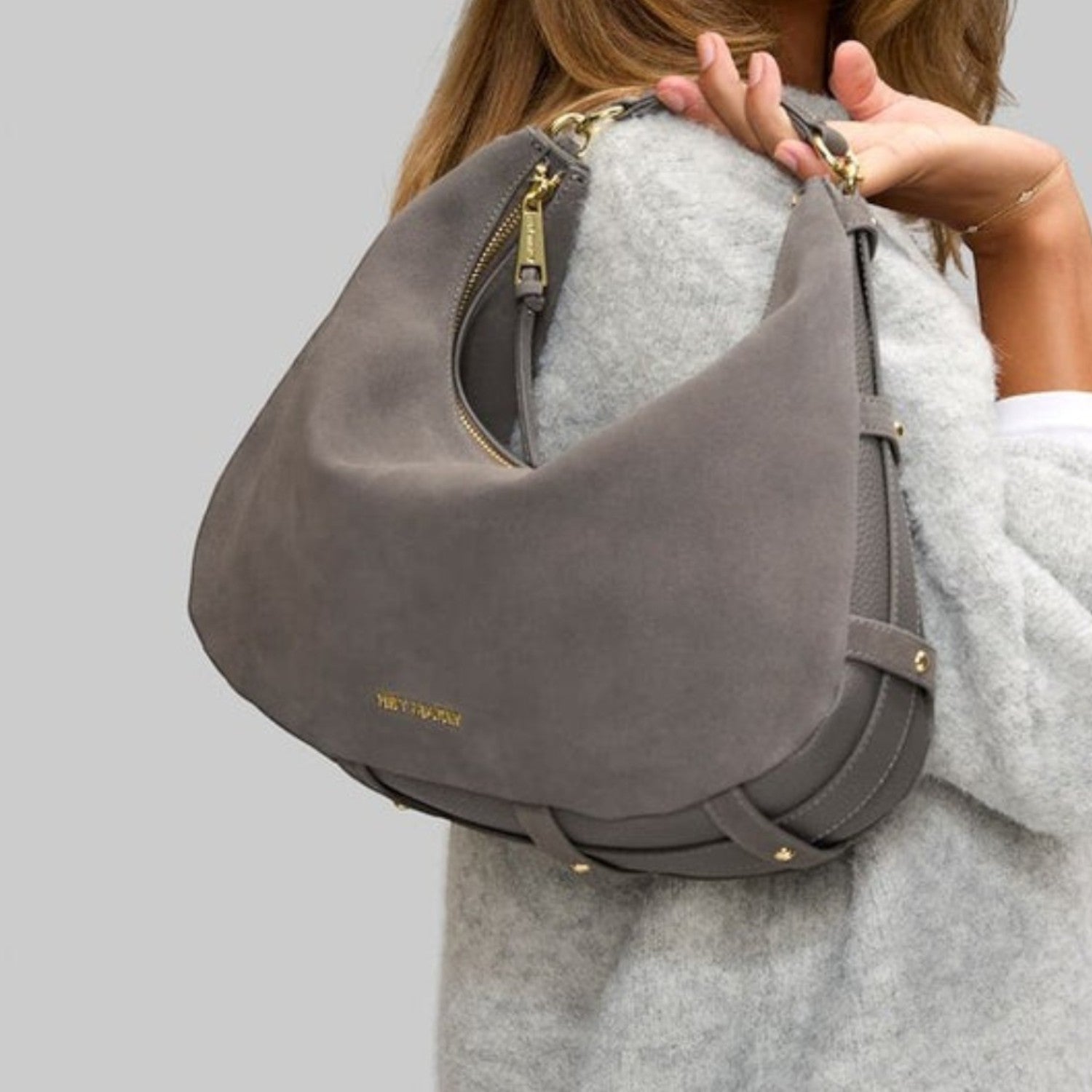 Lieblingstasche Lifetime Sister Suede M grey hobo bag with gold hardware worn over the shoulder by a woman