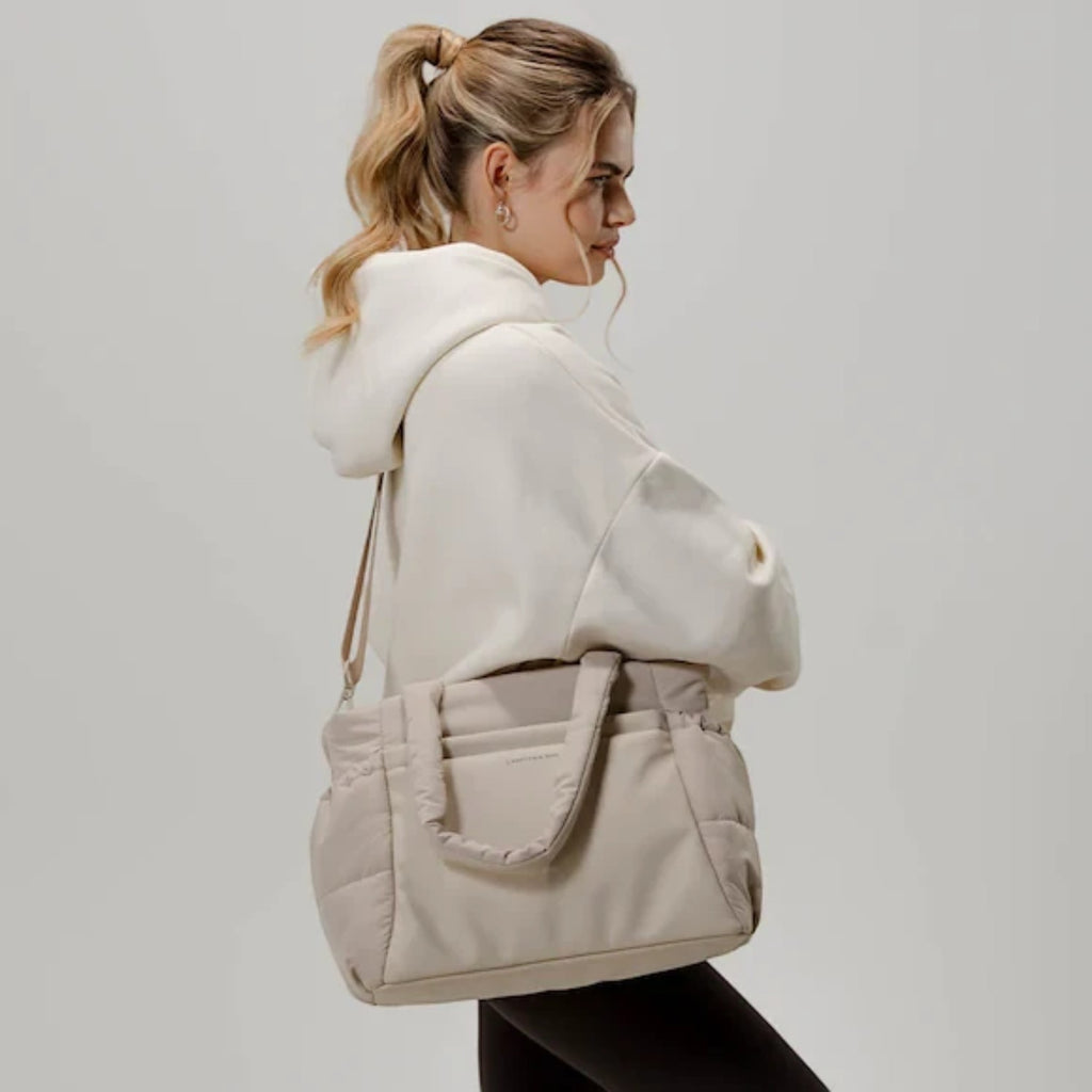 Lieblingstasche Hellvi Cloud Medium beige padded shoulder bag with quilted texture worn by a woman in a hoodie