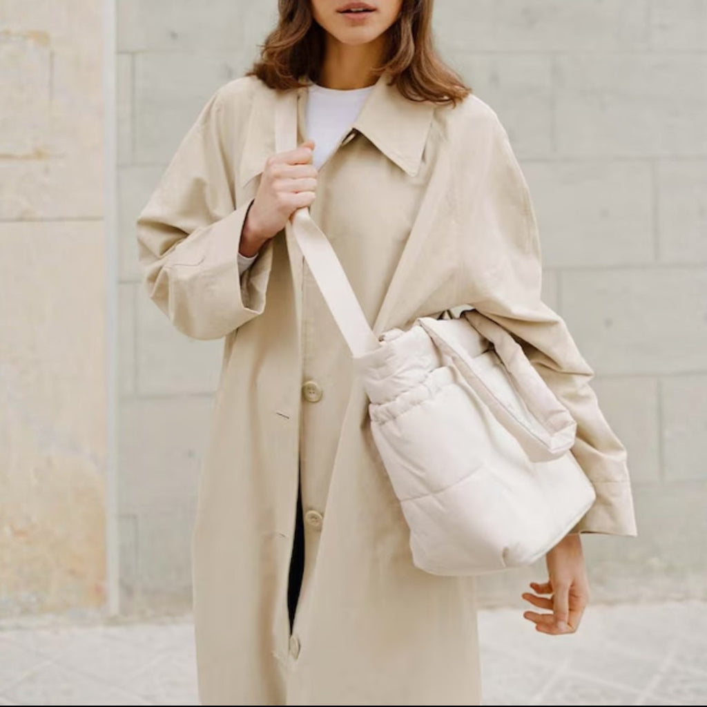 Lieblingstasche Hellvi Cloud Medium bag in cream with padded design worn by a woman in a beige trench coat