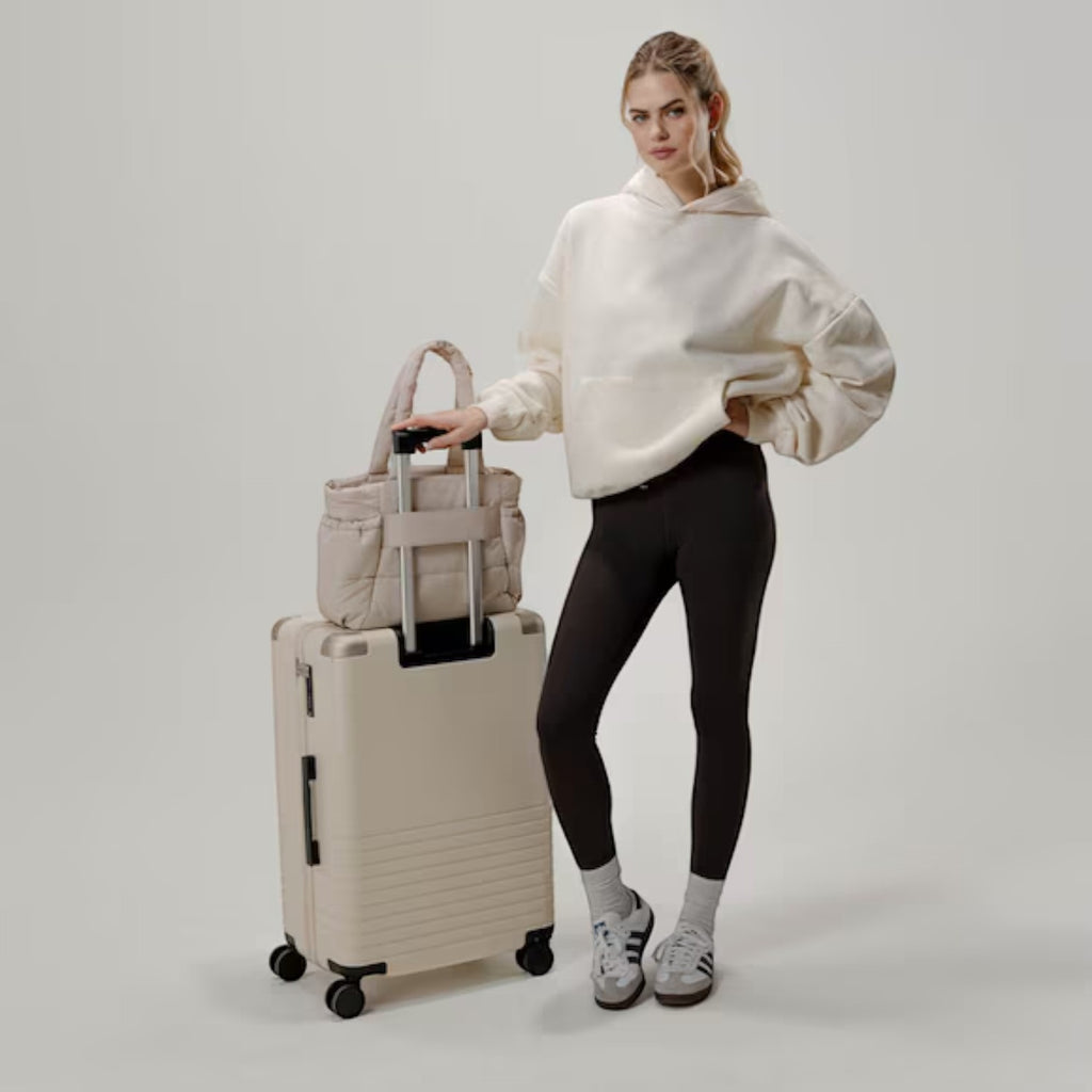 Lieblingstasche Hellvi Cloud Medium beige quilted bag on a suitcase with a model in casual sportswear