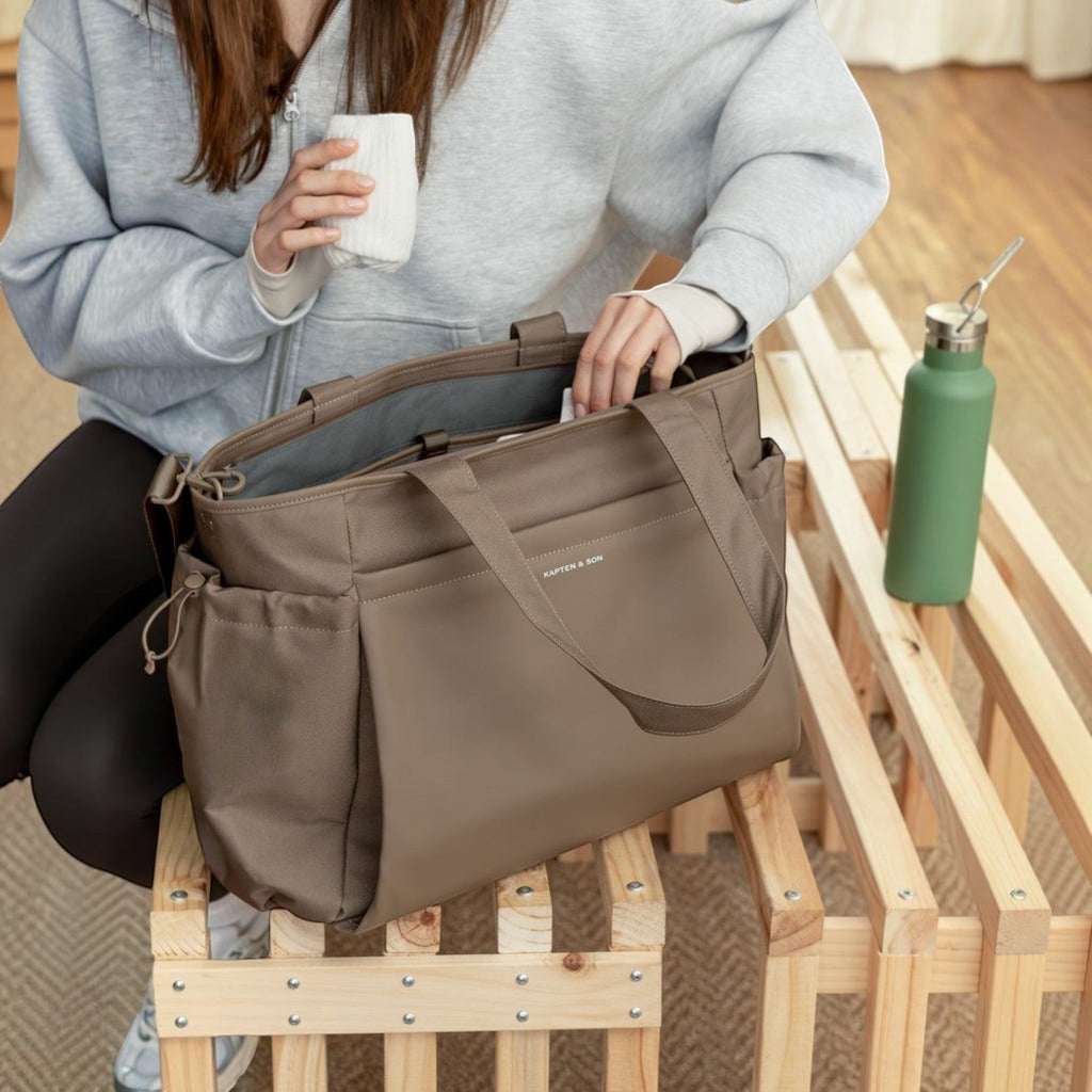 Lieblingstasche Hellvi Pro Large taupe tote bag with side pockets and top handles held by a person