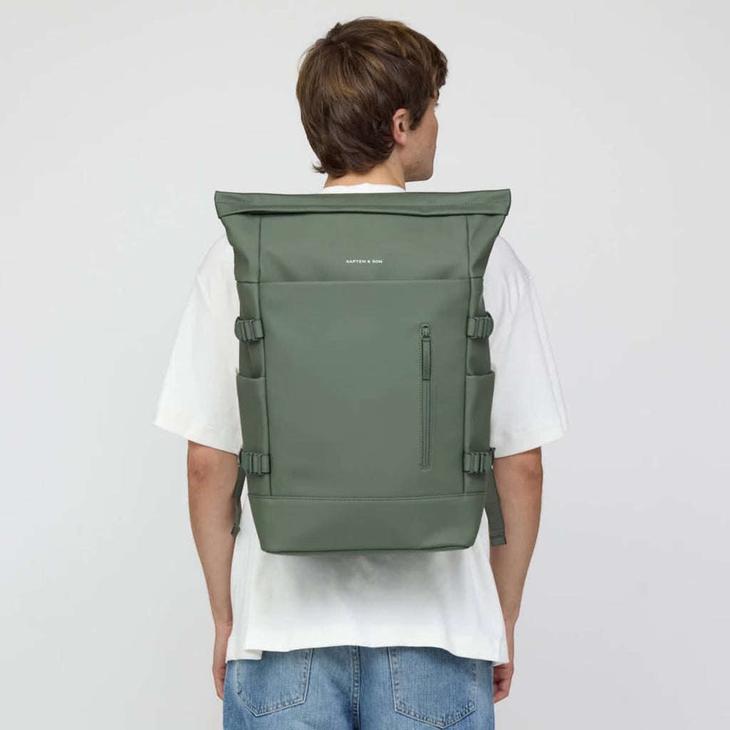 Lieblingstasche Helsinki Pro rolltop backpack in sage green worn by a man in a white t-shirt, back view