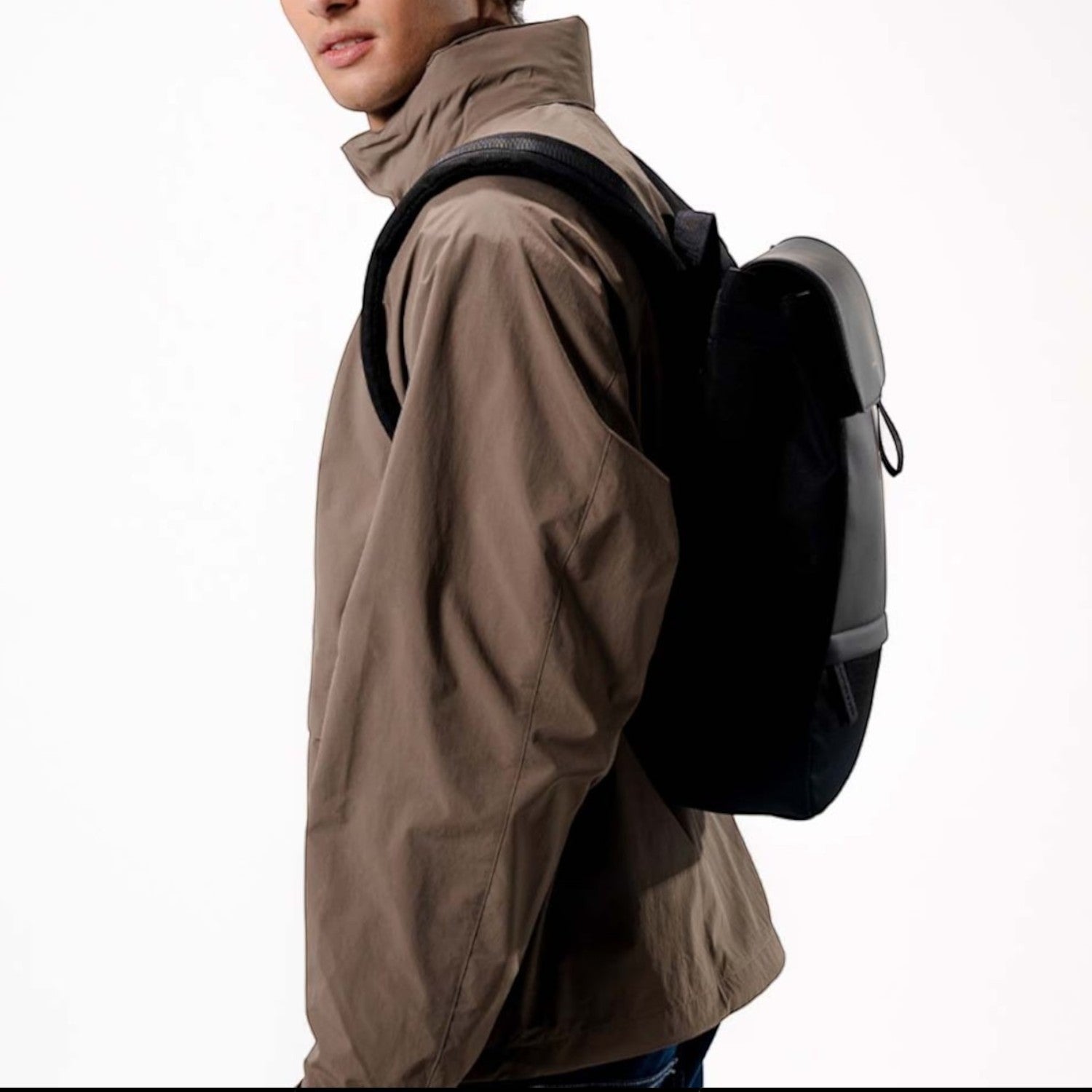 Lieblingstasche Kapten & Son Fyn minimalist black backpack worn by a man in a brown jacket against a white background