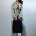 Lieblingstasche Kapten & Son Lund Pro black rolltop backpack held by a woman in a beige suit