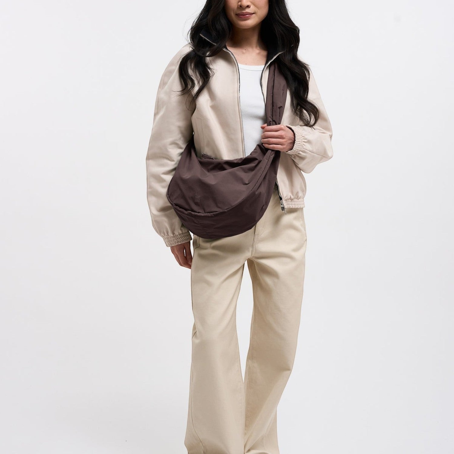 Model wearing a large brown Lieblingstasche Moon Bag Ruffle crossbody bag with a beige jacket and trousers