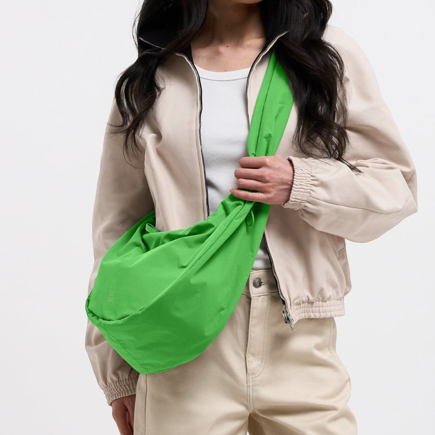 Lieblingstasche large green Moon Bag with ruffle detail worn as a crossbody bag by a model in a beige jacket