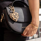 Lieblingstasche heart charm with a leopard print pattern attached to a black leather handbag