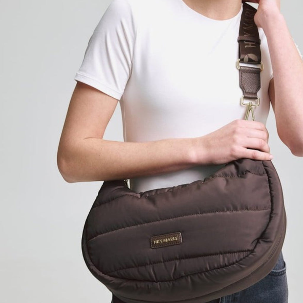 Lieblingstasche Lifetime Buddy M brown quilted crescent shoulder bag with branded strap worn by a smiling woman