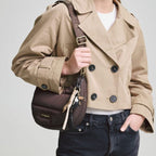 Lieblingstasche Lifetime Buddy S brown quilted crossbody bag with branded strap worn by a woman in a beige trench coat