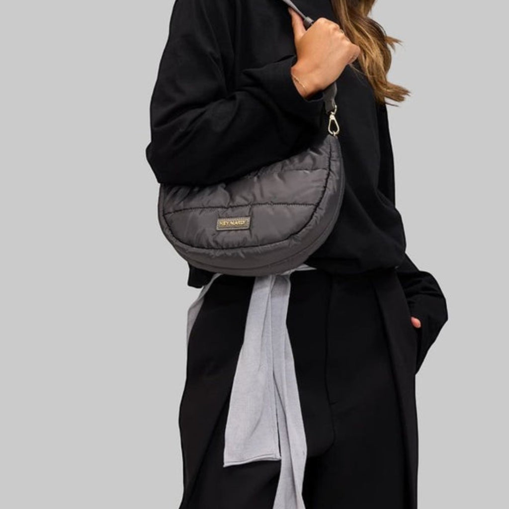 Woman wearing a grey quilted Lieblingstasche Lifetime Buddy S crescent shoulder bag with gold hardware