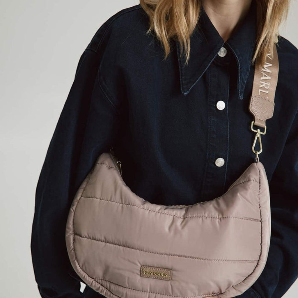 Lieblingstasche Lifetime Buddy M taupe quilted crescent shoulder bag with branded strap worn by a woman