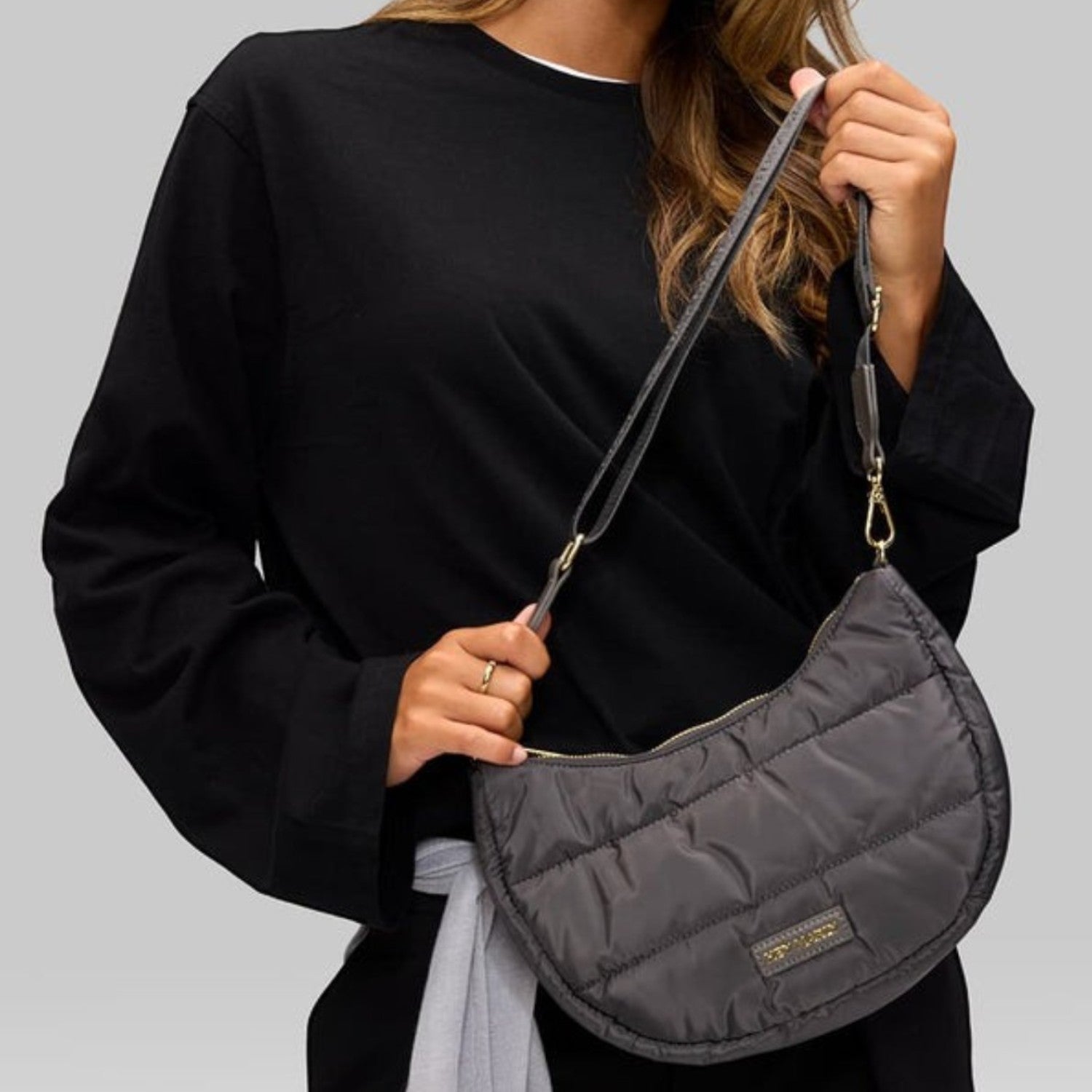 Lieblingstasche Lifetime Buddy S quilted charcoal grey crescent crossbody bag worn by a woman