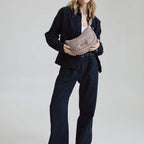 Model wearing a Lieblingstasche Lifetime Buddy S quilted taupe crossbody bag with a dark denim outfit