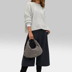 Lieblingstasche Lifetime Sister Suede M grey suede hobo bag held by a model wearing a grey sweater and black culottes