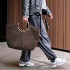 Lieblingstasche Loopbag Hobo in brown teddy fleece with round wooden handles carried by a person in casual attire