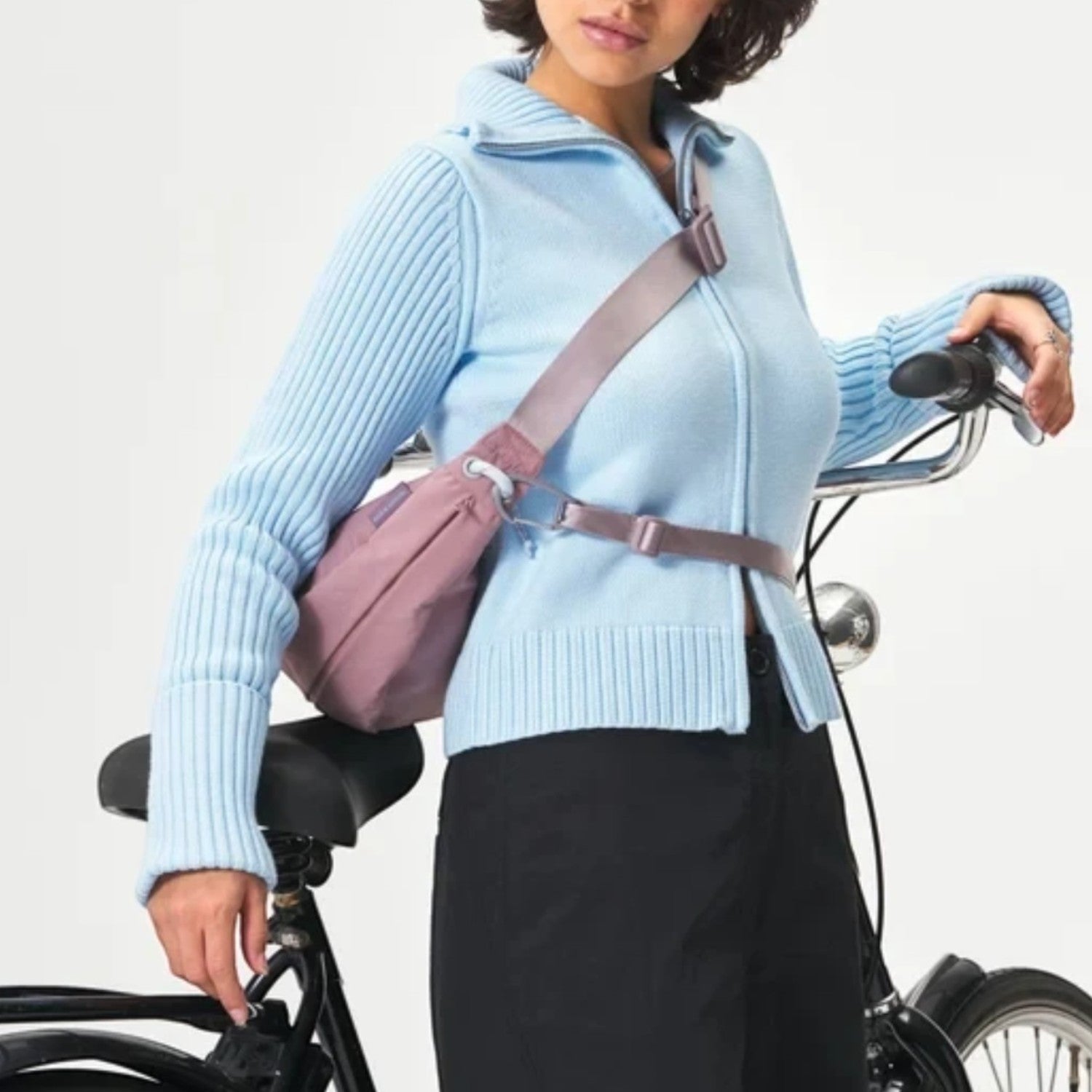 Lieblingstasche mauve water-resistant sling bag worn crossbody by a cyclist with 3-point strap for secure fit