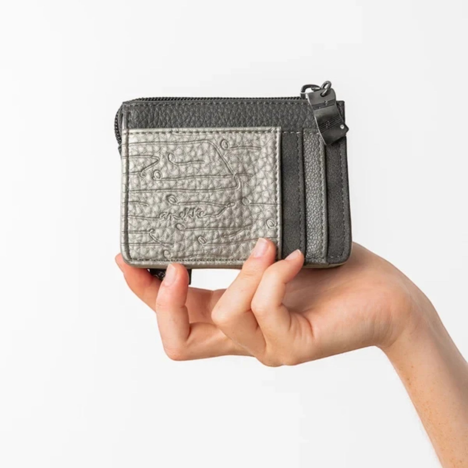 Lieblingstasche card holder in metallic silver and dark grey textured leather with a zip closure held in a hand