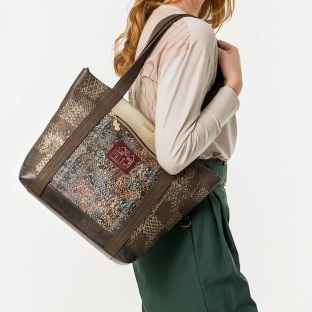 Lieblingstasche shoulder bag with metallic bronze, blue, and brown textured panels worn by a woman on her shoulder.