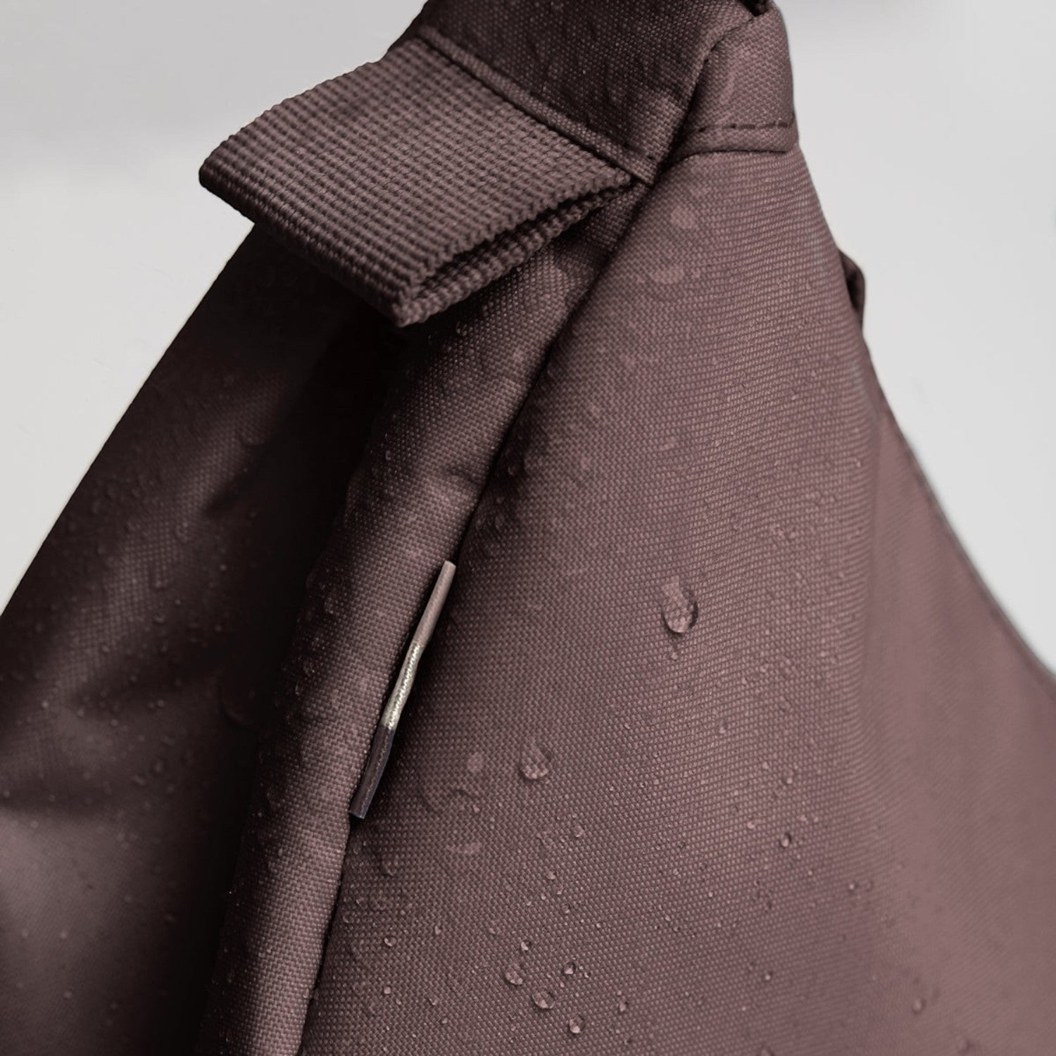 Lieblingstasche Moon Bag Small in dark brown water-repellent fabric with visible water droplets on the surface
