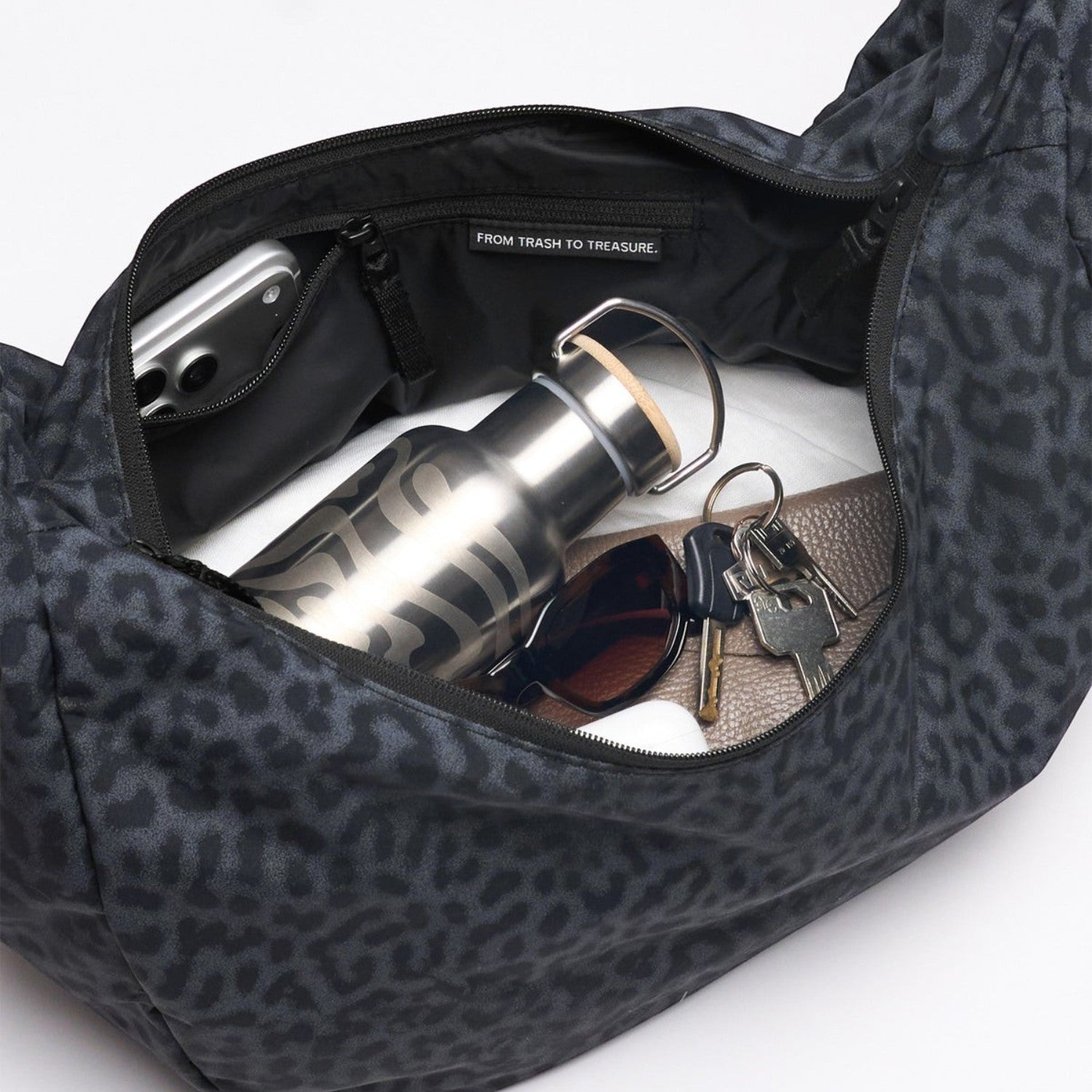 Lieblingstasche Moon Bag Ruffle Large in black leopard print with an open interior containing a water bottle and keys.