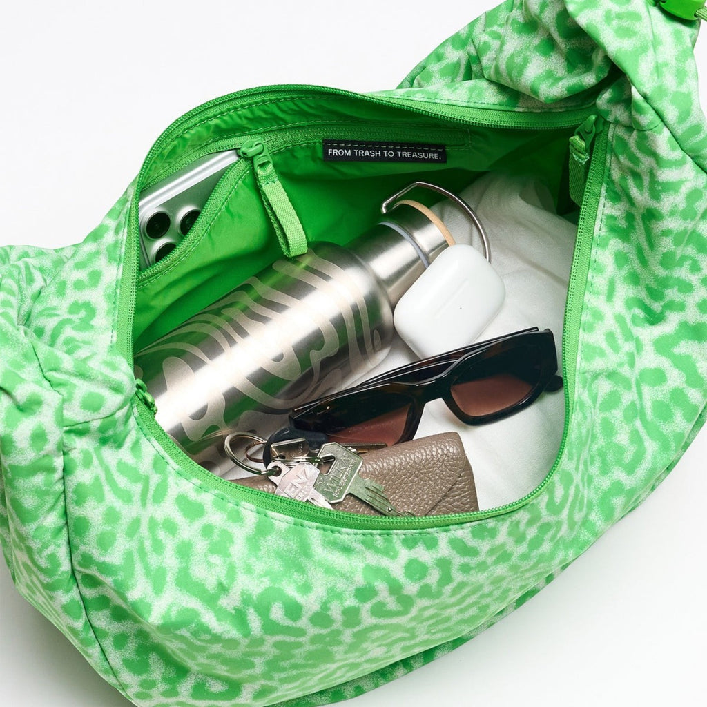 Lieblingstasche Moon Bag Ruffle Large in green animal print, showing interior with water bottle, keys, and accessories.