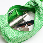 Lieblingstasche Moon Bag Ruffle Large in green animal print, showing interior with water bottle, keys, and accessories.