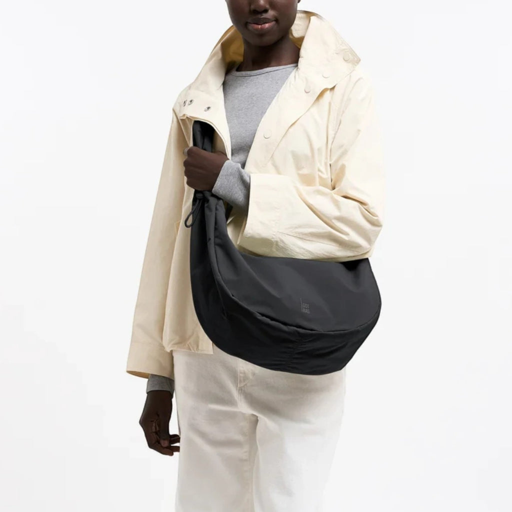 Lieblingstasche Moon Bag Ruffle Large in black, made from recycled fishing nets, worn as a crossbody bag by a model.