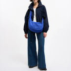 Lieblingstasche Moon Bag Ruffle Large in blue, worn as a crossbody bag by a woman in a dark jacket and jeans.