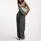 Lieblingstasche Moon Bag Ruffle Large in sage green, worn as a crossbody bag by a woman in a brown long-sleeve top.