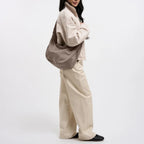 Lieblingstasche Moon Bag Ruffle Large in taupe, worn as a crossbody bag by a woman in beige clothing.
