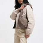 Lieblingstasche Moon Bag Ruffle Large in taupe, worn as a crossbody bag by a model in a beige jacket.
